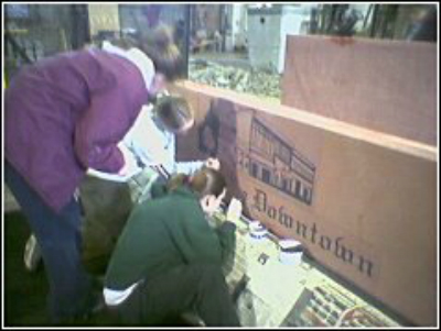 sm kids painting Grandview sign with three people working